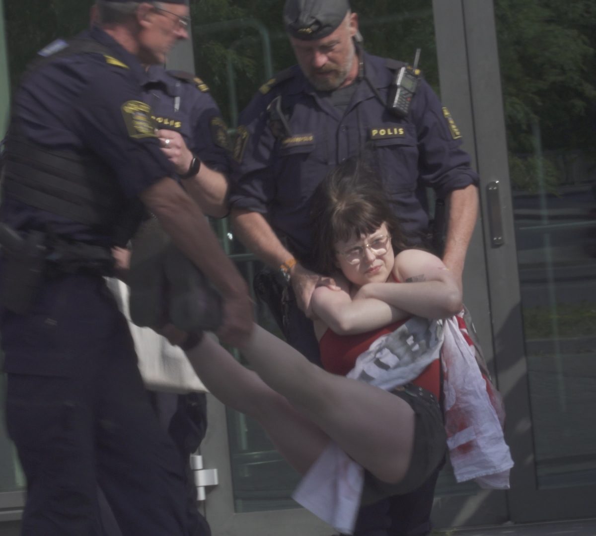 A young lady being carried by two policemen against her will.